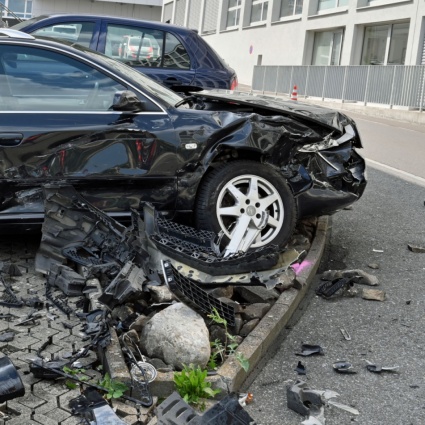 Centra prima una pensilina, poi diverse auto, un muro e infine un palo